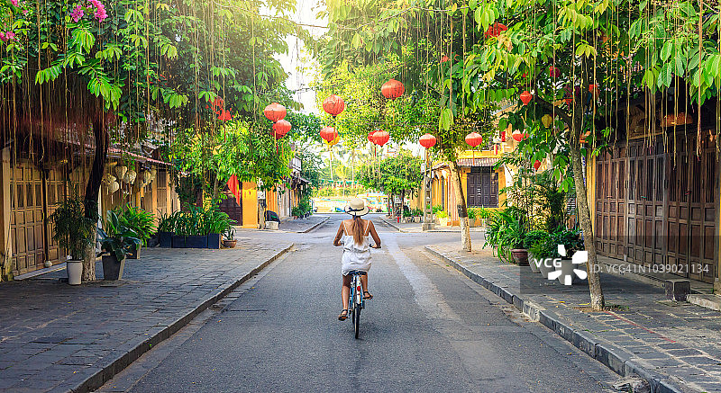在越南的会安老城，妇女们在上午骑自行车参观图片素材