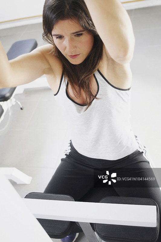 一个中年妇女在健身房锻炼的特写图片素材
