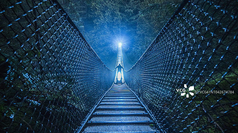 夜晚，树林中的吊桥上出现了神秘的剪影图片素材