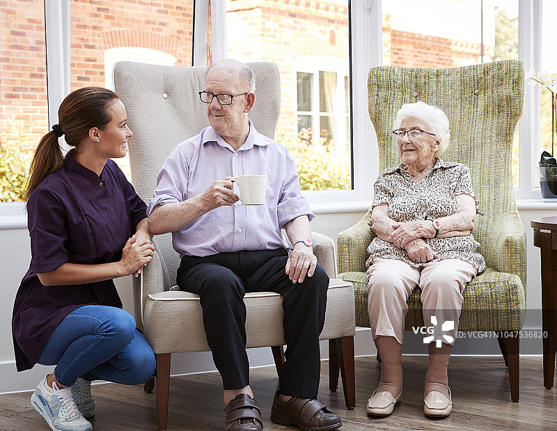 在退休之家，男女居民坐在椅子上与护理员交谈图片素材