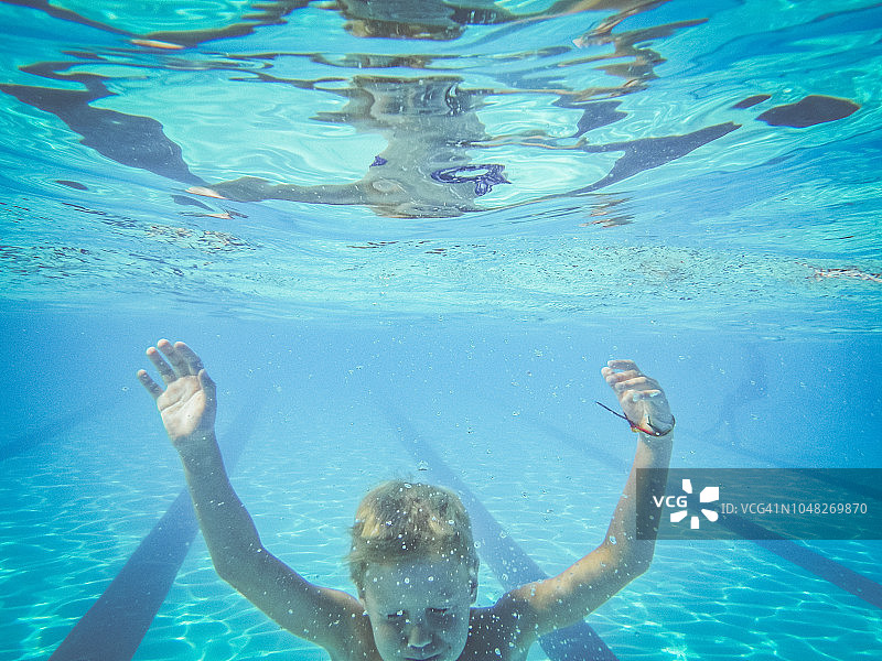 男孩游泳到游泳池的底部图片素材