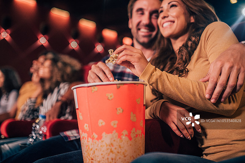 微笑的夫妇在电影院吃爆米花图片素材