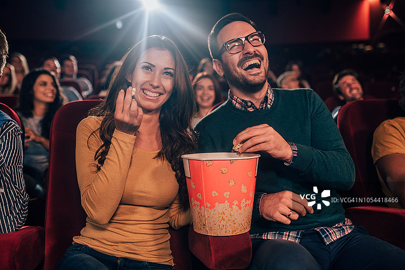 在电影院微笑着吃爆米花的人们图片素材