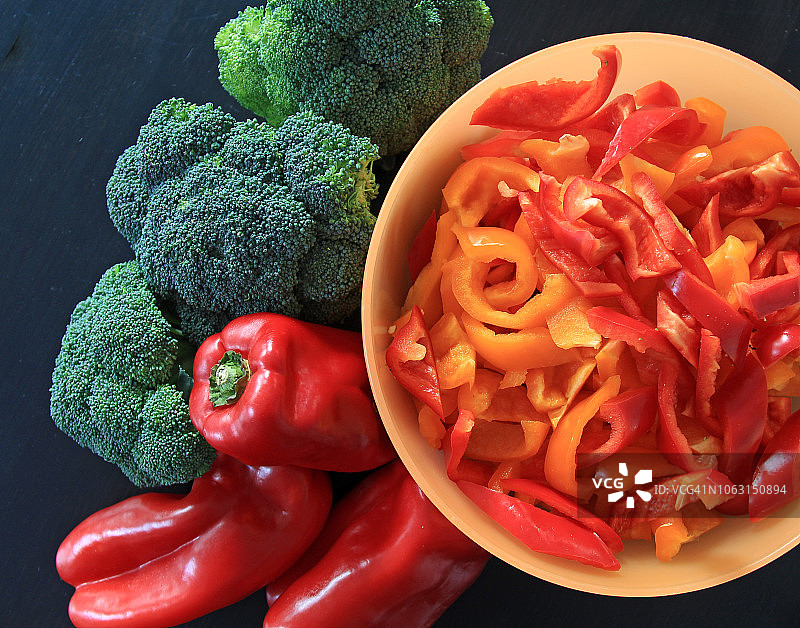 花椰菜，三个红辣椒和一碗切碎的红黄椒图片素材