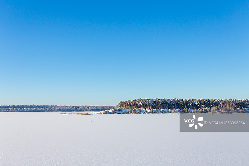 冰封的湖面上有冰雪，阳光明媚的冬日。森林图片素材