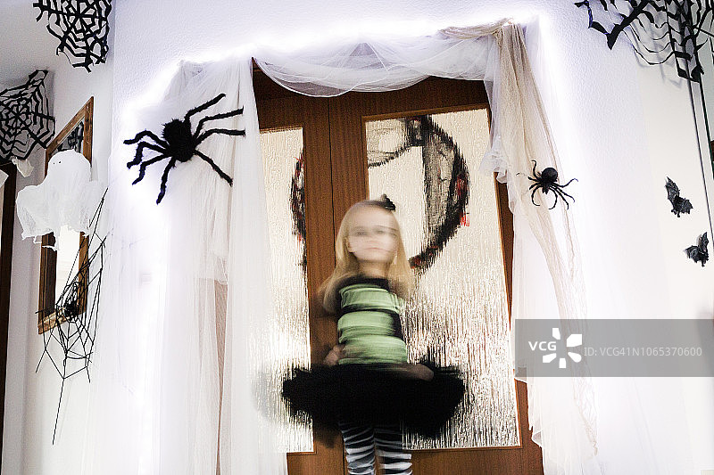 模糊的运动的女孩在一个黑色的裙子和周围的幽灵万圣节装饰旋转图片素材