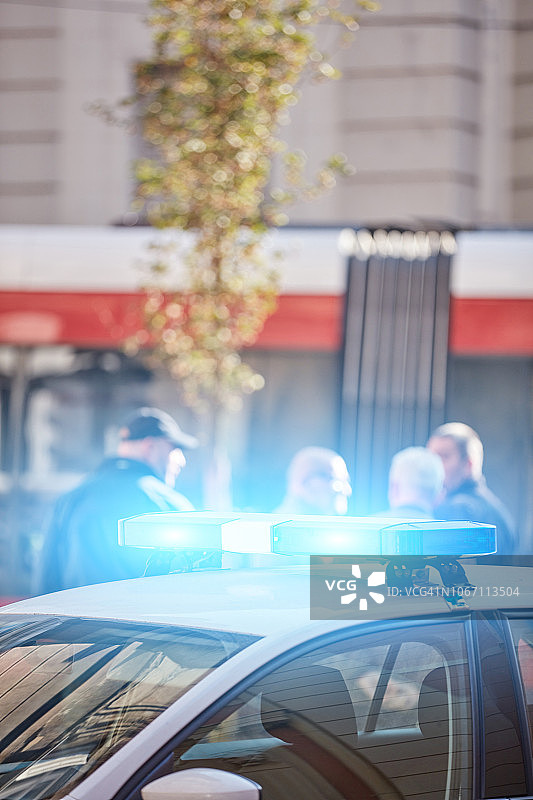 在交通/城市环境的犯罪现场上开着蓝色灯的警车。图片素材