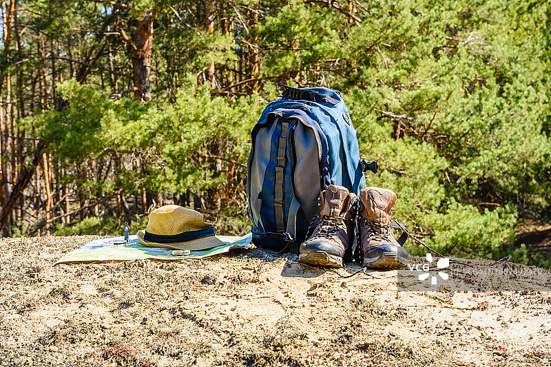 背包，旅游靴，地图，指南针和帽子在一个针叶林的地面上图片素材