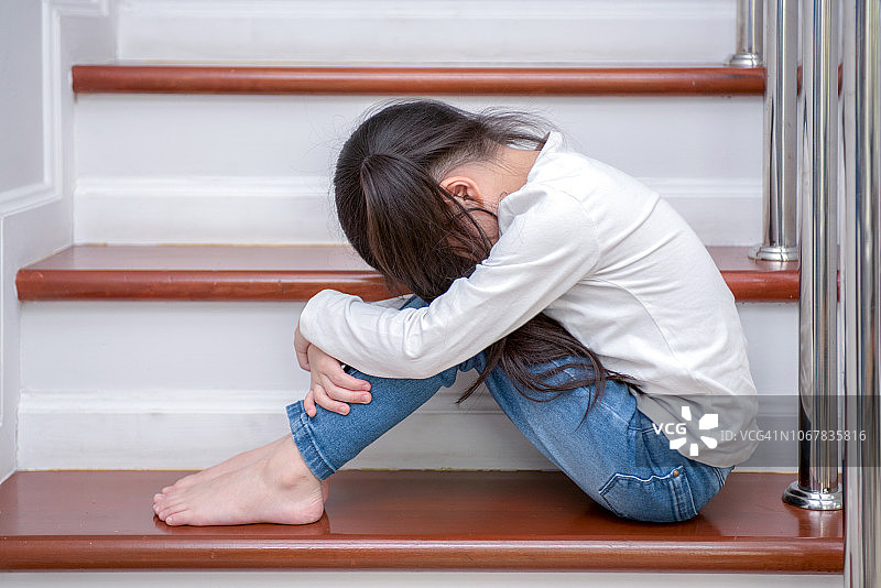 悲伤的小女孩坐在楼梯上图片素材