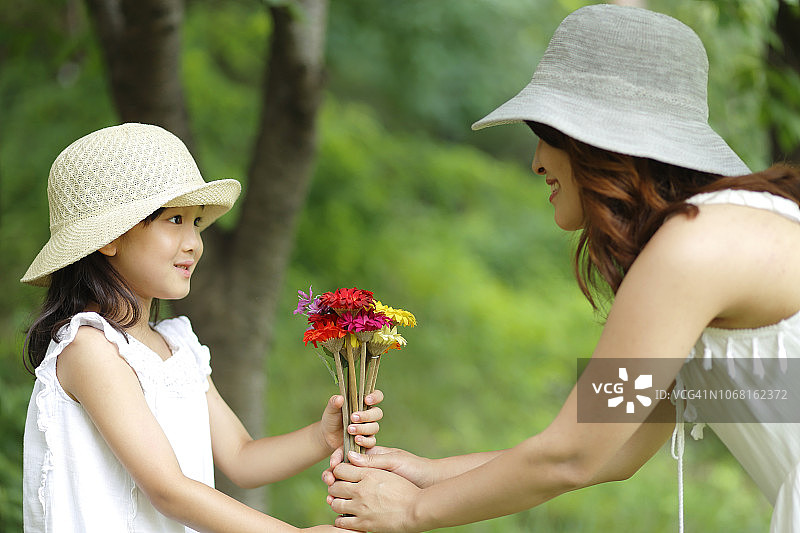 母亲和女儿手捧鲜花在公园里图片素材