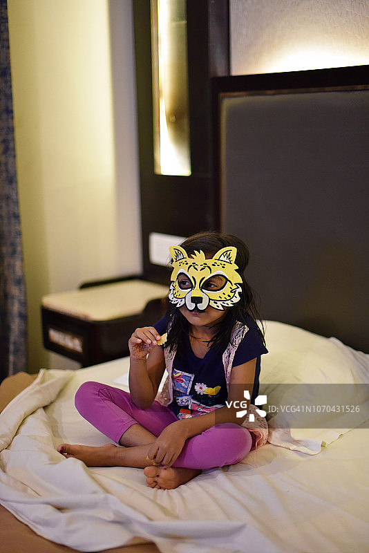 小女孩戴着动物面具躺在床上图片素材