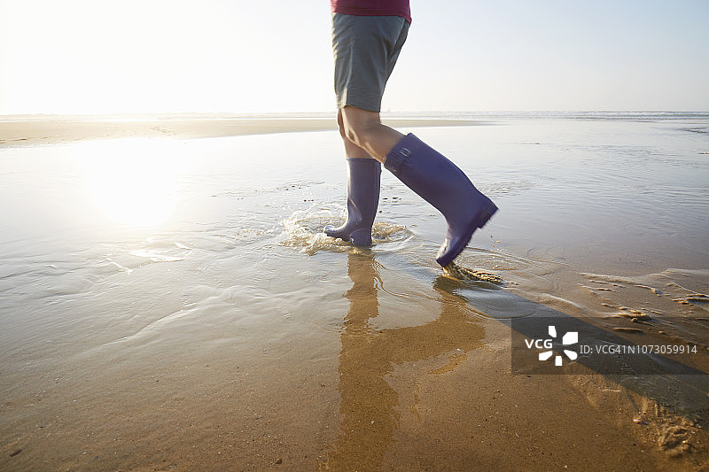 穿着胶靴在海滩上散步的女人图片素材