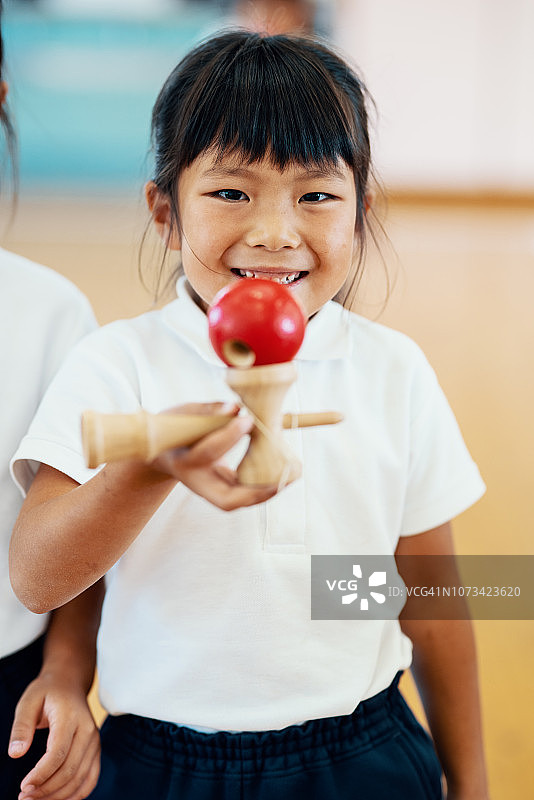 一个小女孩在幼儿园拿着她的球杯玩具的肖像图片素材