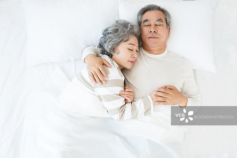 微笑的老夫妇躺在床上互相耳语图片素材