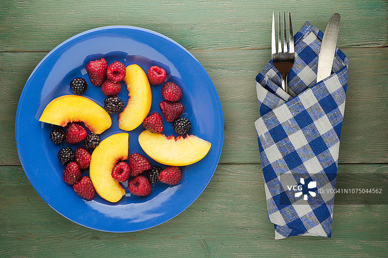 饮食,健康食品。黑莓、覆盆子、油桃一盘盘上。木制背景上的素食图片素材