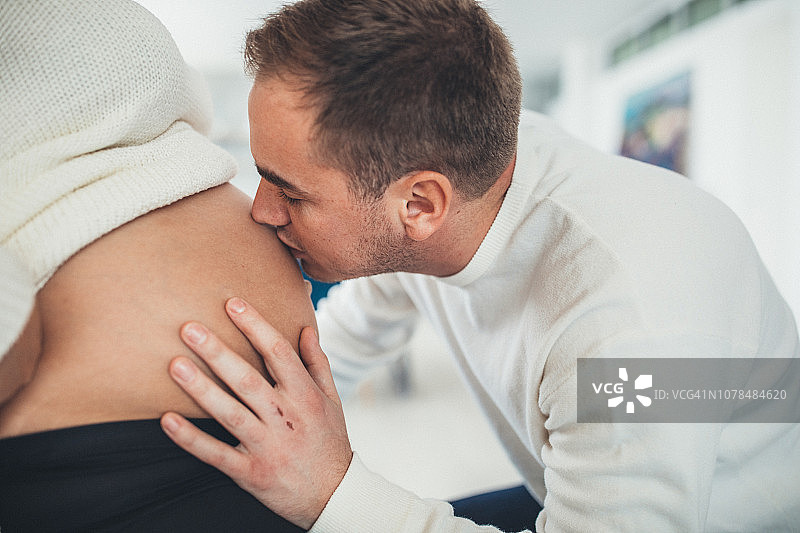 丈夫亲吻怀孕妻子的肚子图片素材