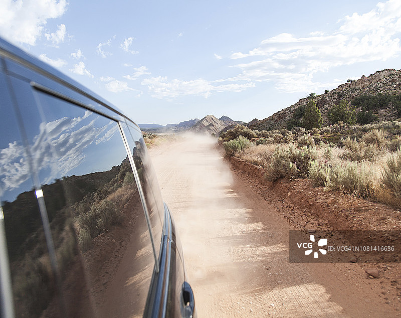 沙漠里的土路上开着一辆黑色轿车图片素材