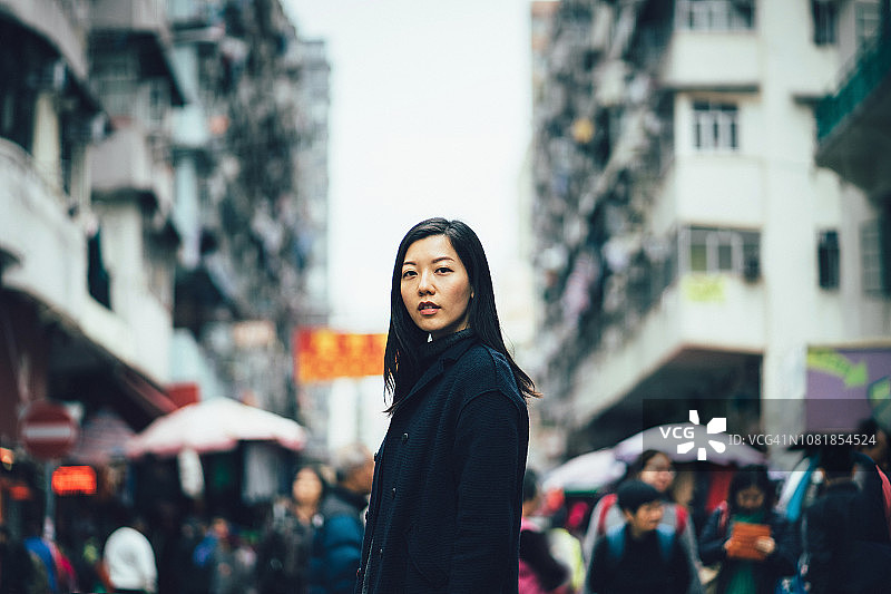 年轻的亚洲妇女站在繁忙的香港当地城市街道图片素材