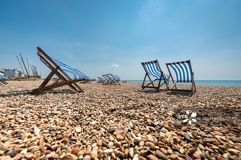 英国布莱顿海滩上，海风吹拂下的躺椅图片素材