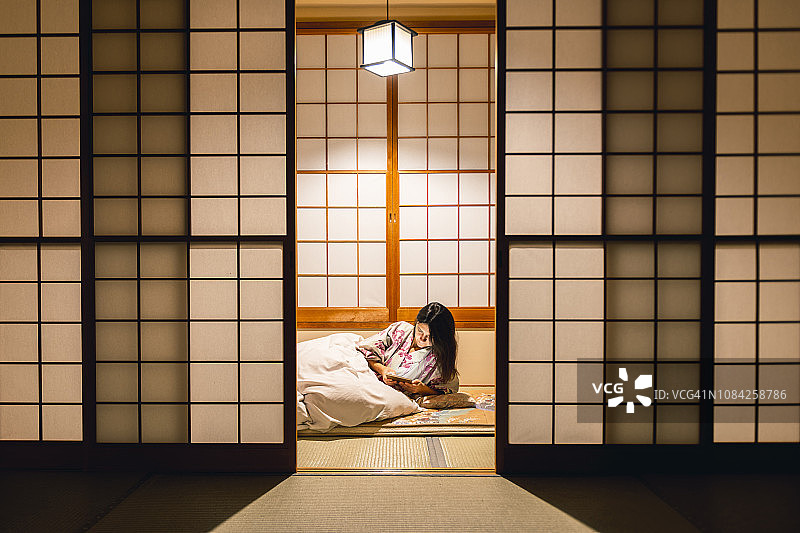 在传统的日式旅馆里用平板电脑工作的女人图片素材