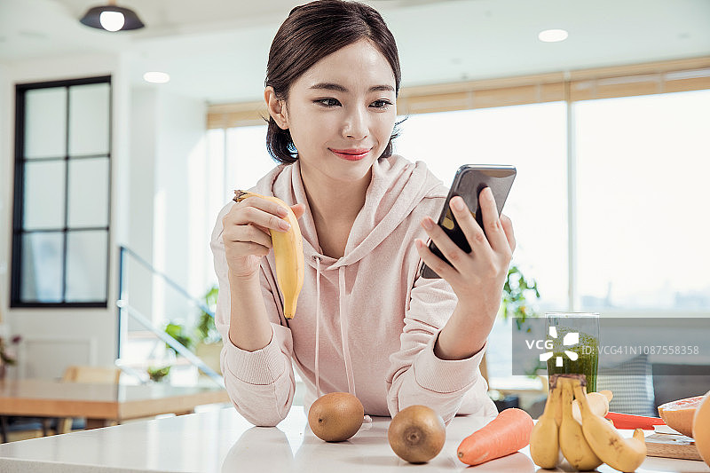 吃香蕉看智能手机的女人图片素材