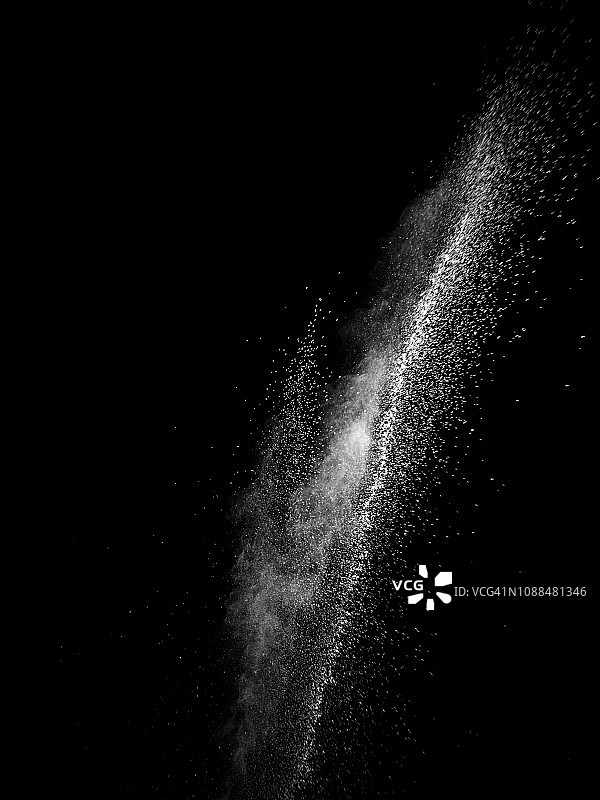 一团白色的粉末颗粒在黑色的背景上碰撞而产生的爆炸。图片素材