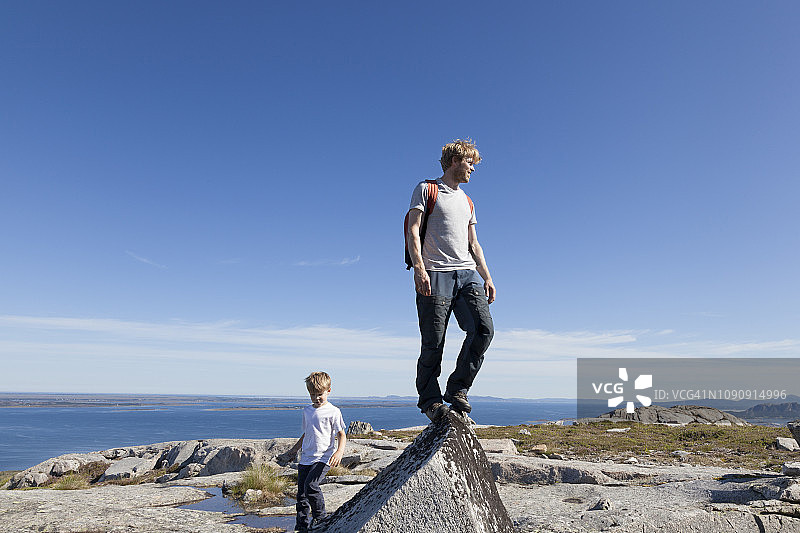 挪威莫尔奥格罗姆斯达尔，男孩和父亲从岩石顶部俯瞰风景图片素材