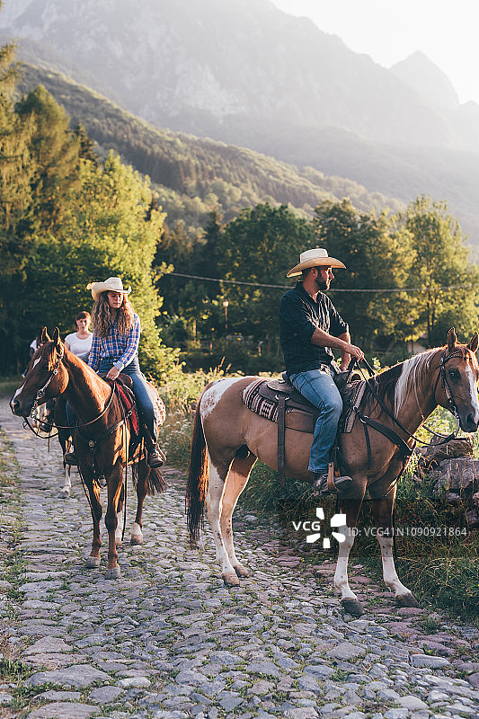 成年朋友在乡村鹅卵石路上骑马，Primaluna，特伦蒂诺-上阿迪杰，意大利图片素材