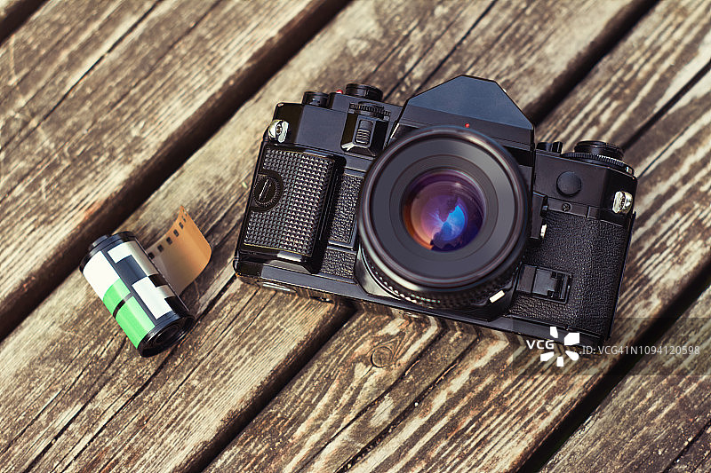 复古单镜头反光专业胶片相机在木桌上有一卷胶卷图片素材