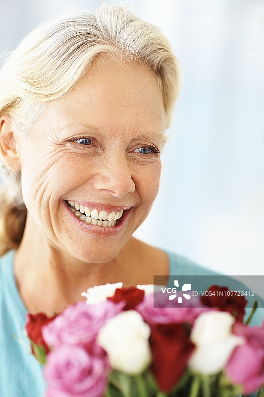 快乐成熟的女人捧着一束玫瑰图片素材