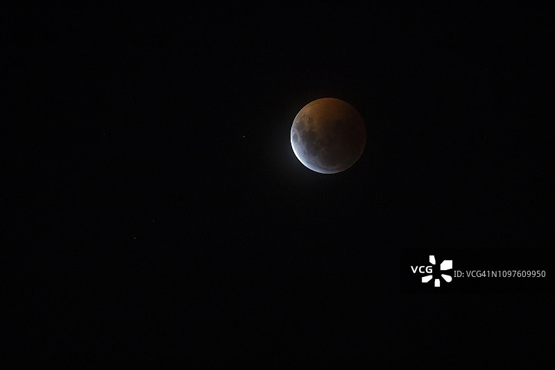 来自智利圣地亚哥的红色满月月食，这是一个从南半球看到的地球阴影穿过月球表面并将其变成红色和黄色的惊人天文事件图片素材