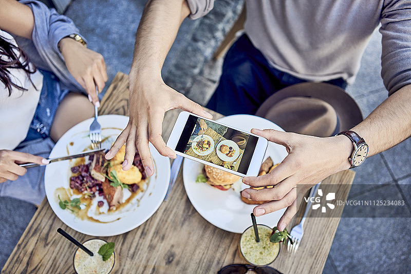 一对夫妇在户外餐厅拍摄食物的俯视图图片素材