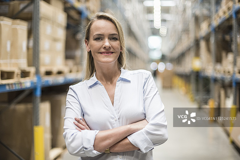 微笑的女人在工厂仓库的肖像图片素材