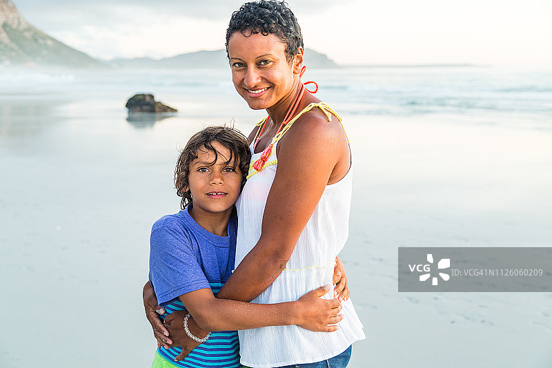 母亲和儿子在日落的海滩上的肖像图片素材