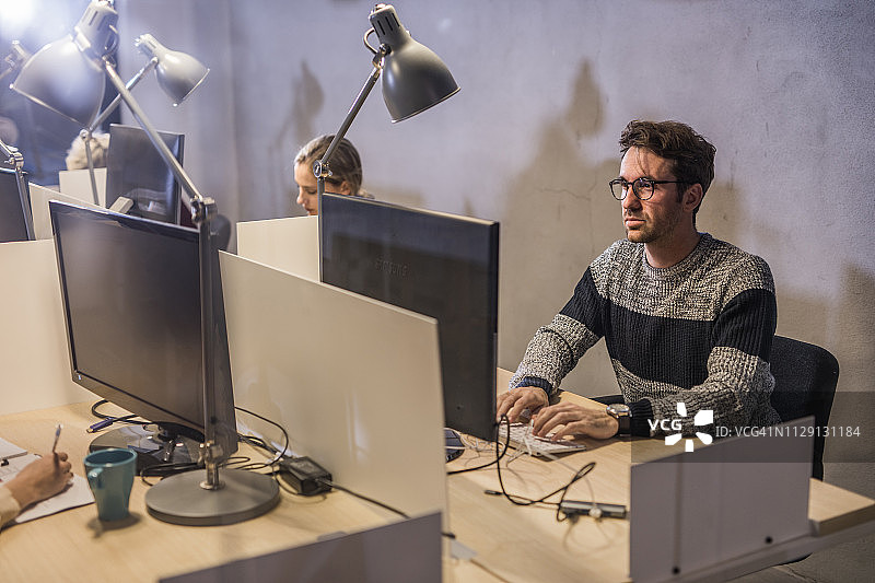 年轻的企业家在公司办公室用台式电脑工作。图片素材