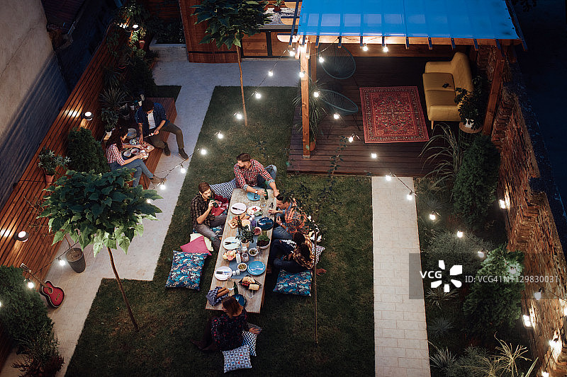 俯瞰一个多民族的朋友享受晚餐聚会在院子里图片素材