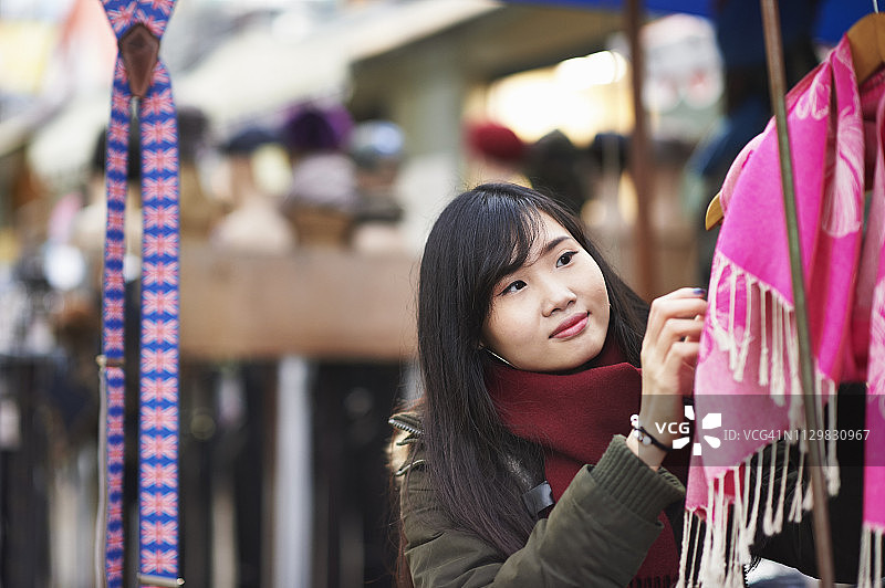 一个年轻女子在市场的摊位上看围巾图片素材