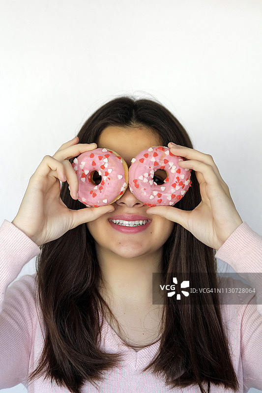 有趣的美女透过粉色的甜甜圈看。饮食,饮食的概念。垃圾食品，减肥，减肥图片素材