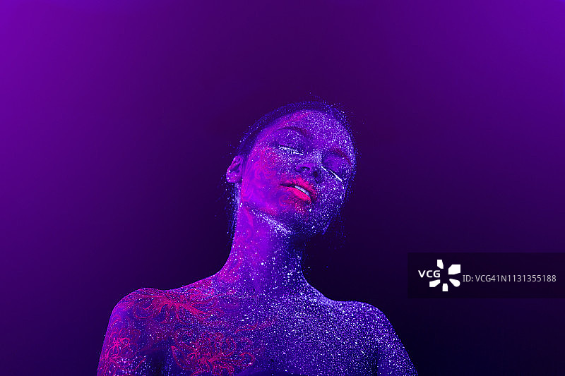 一个美丽的女孩紫色外星人的肖像。紫外线人体艺术，蓝色的夜空，星星和粉红色的水母，图片素材