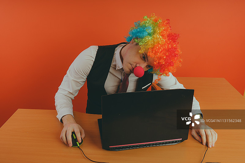 戴小丑假发的办公室职员，在工作中扮演小丑的角色。图片素材