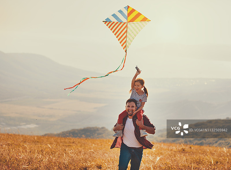 幸福的家庭父亲和孩子女儿在草地上放风筝图片素材