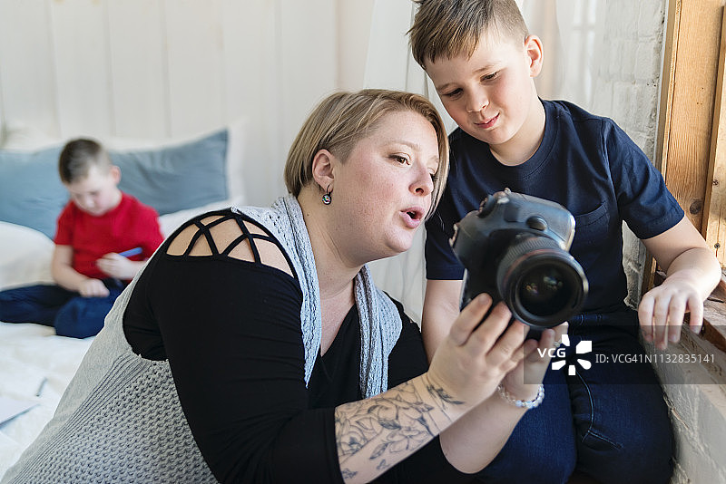 职业摄影师母亲和她的两个儿子一起工作。图片素材