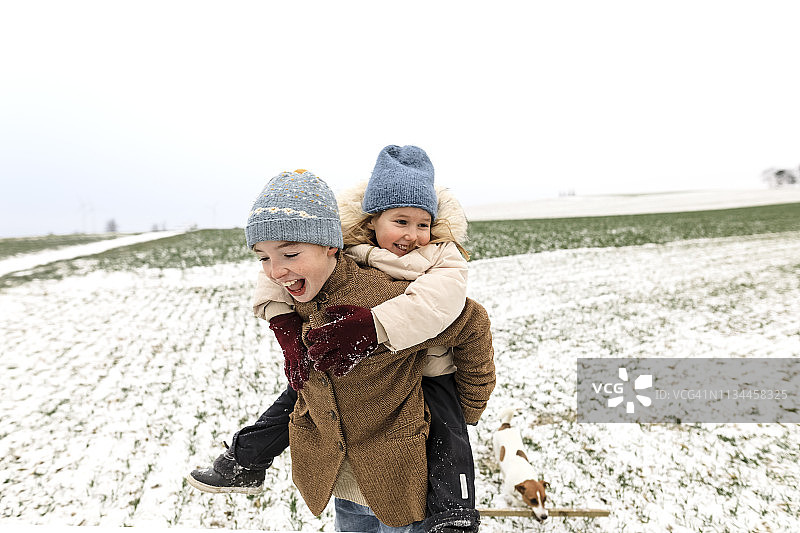 男孩背着快乐的姐姐在冬天的风景图片素材