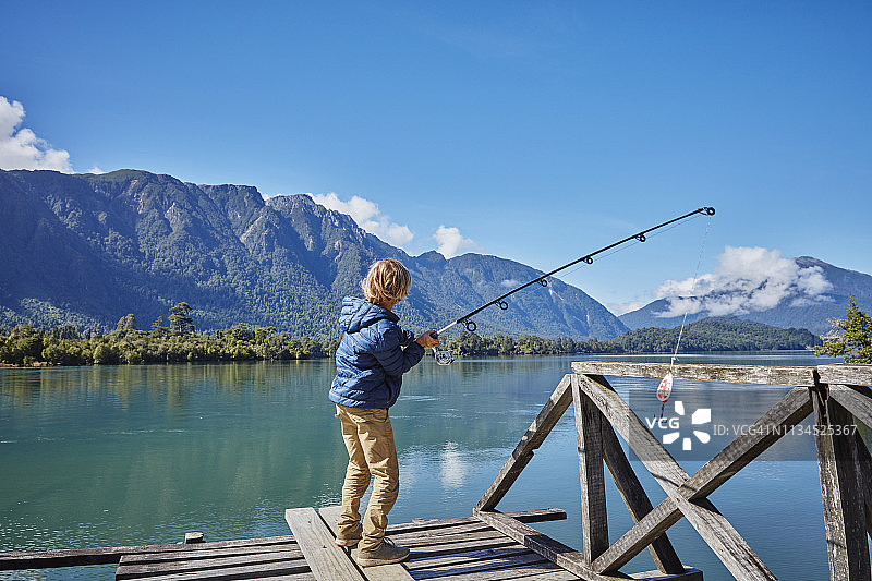 智利，Chaiten, Lago Rosselot，男孩站在防波堤上在湖中钓鱼图片素材