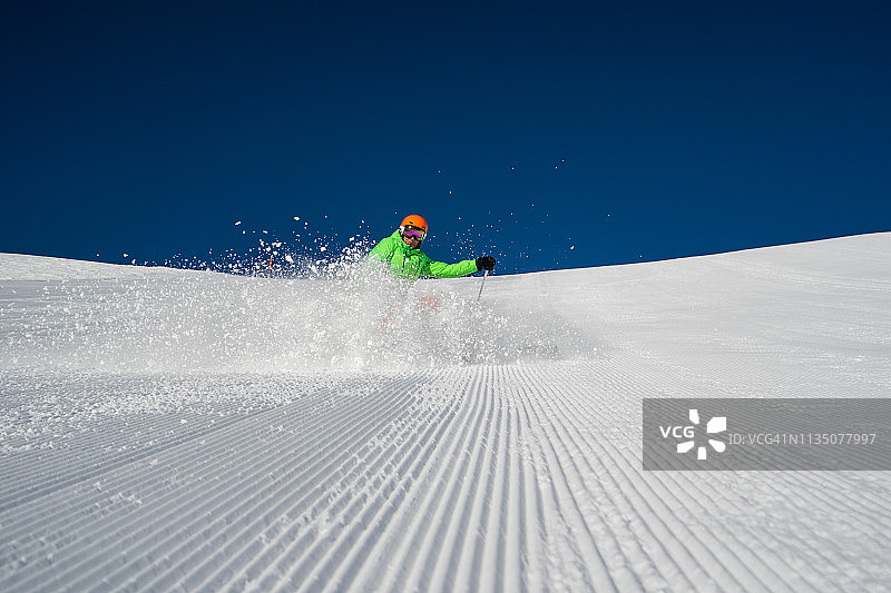 一名滑雪者停在滑雪坡上溅起雪花图片素材