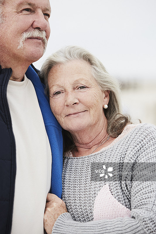 一对老年夫妇站在海滩上拥抱的肖像图片素材