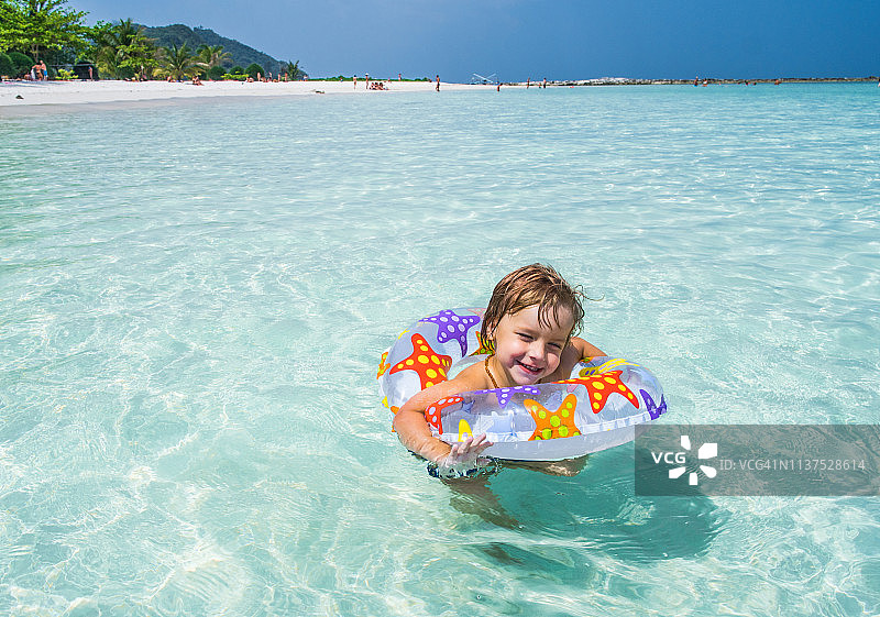 快乐的孩子享受着与充气环在海里游泳。图片素材