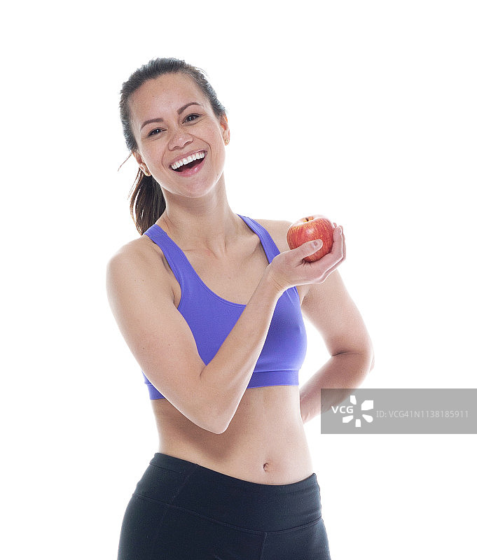 穿着运动服的美女手里拿着一个苹果，很开心图片素材