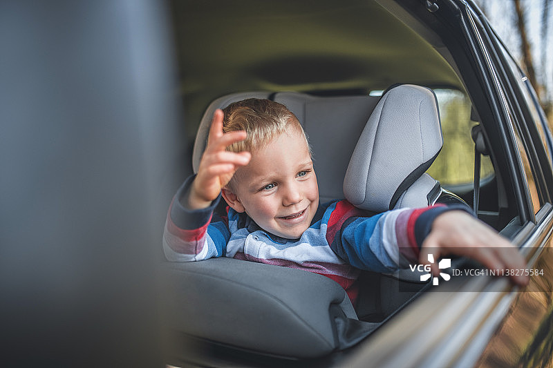 快乐的小男孩坐在汽车安全座椅上图片素材