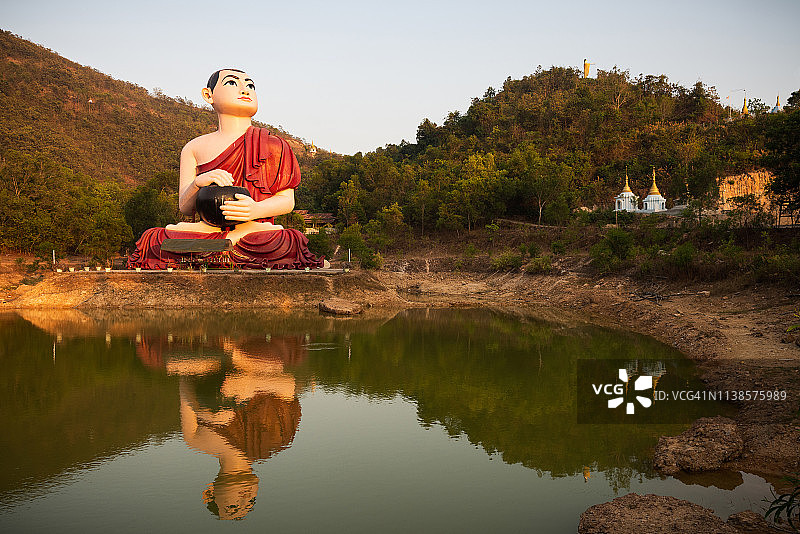 佛教和尚的雕像倒映在一个池塘在Mudon，毛淡棉，孟邦，缅甸图片素材